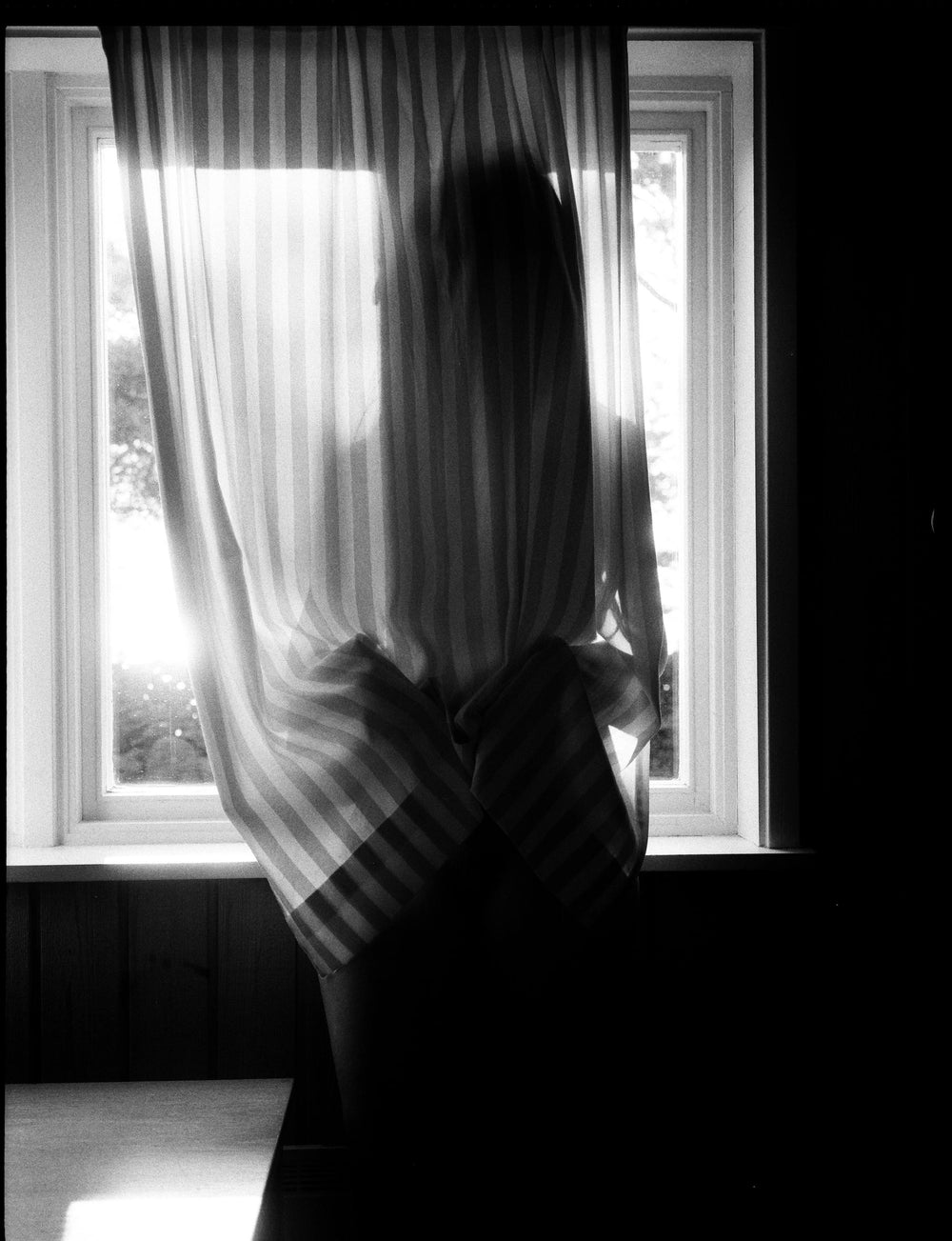a black and white photo of a woman behind a curtain from Lina Scheynius’ photo-essay for Tabayer Jewelry